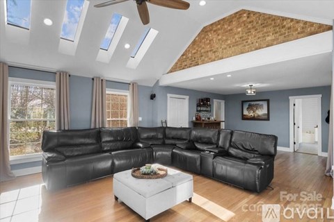 A living room with a black leather sofa and a ceiling fan.