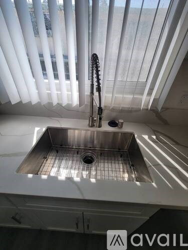 A kitchen sink with a faucet and a window above it.