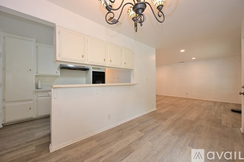 A kitchen with white cabinets and a wooden floor.
