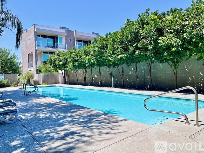 A pool with a slide in front of a building with trees.