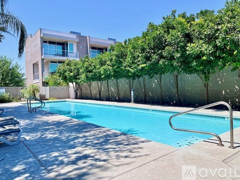A pool with a slide in front of a building with trees.