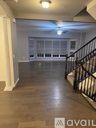A spacious room with a staircase and a ceiling fan.