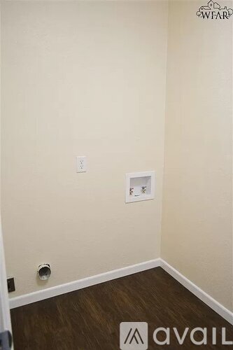 A room with a light switch and a socket on the wall.