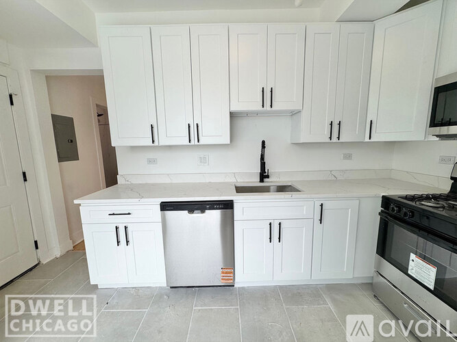 A kitchen with white cabinets and a stainless steel refrigerator.