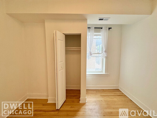 A room with a white door and a window with a view of a building outside.
