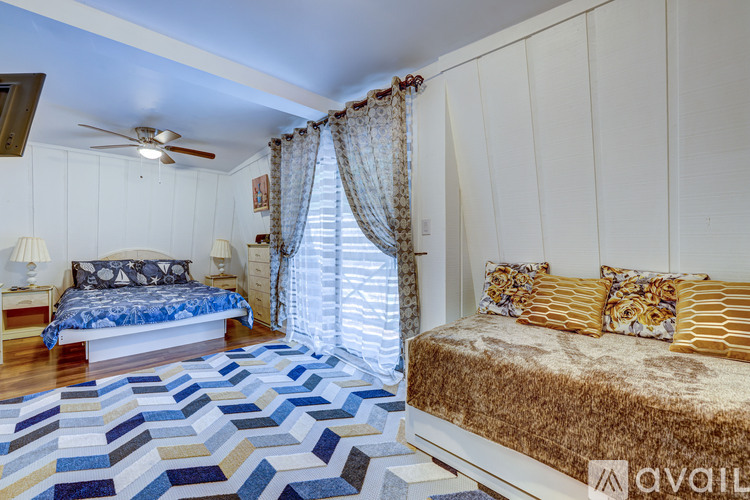 A bedroom with a blue and white patterned rug on the floor.