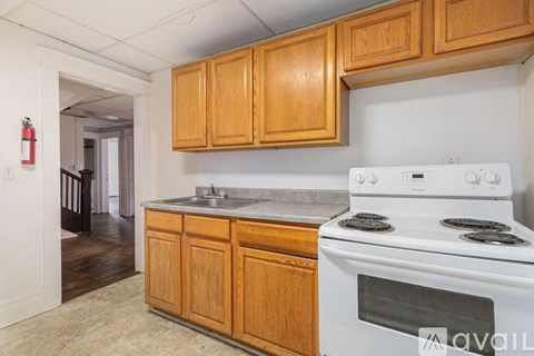 A kitchen with wooden cabinets and a white stove top oven.