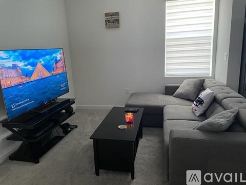 A living room with a television and a grey couch.