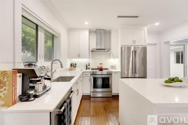 A modern kitchen with stainless steel appliances and white cabinetry.