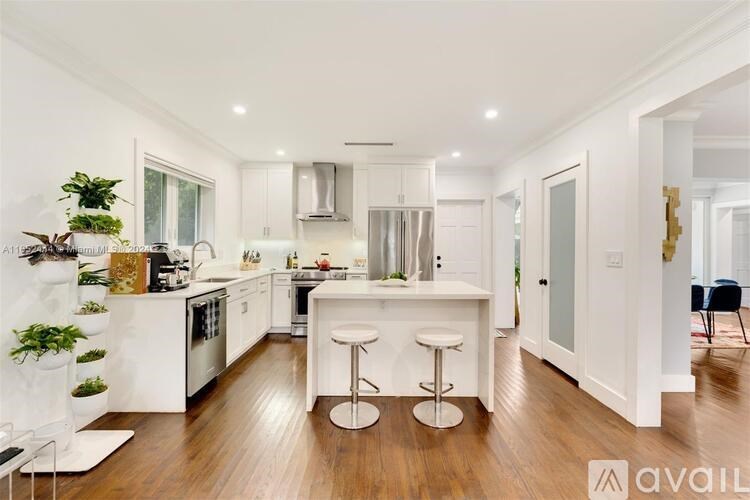 A modern kitchen with white cabinets and a wooden floor.
