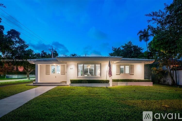 A house with a flag on the front porch is lit up at night.