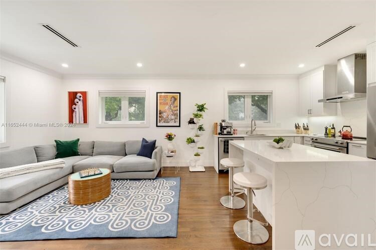 A modern kitchen with a white island and stools.