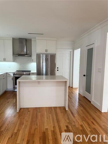A kitchen with white cabinets and a wooden floor.