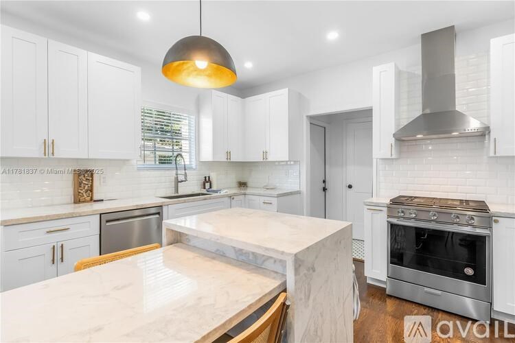 A modern kitchen with a marble countertop and stainless steel appliances.