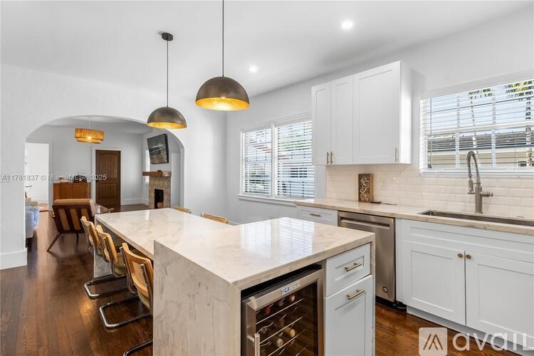 A kitchen with a white countertop and wooden chairs.