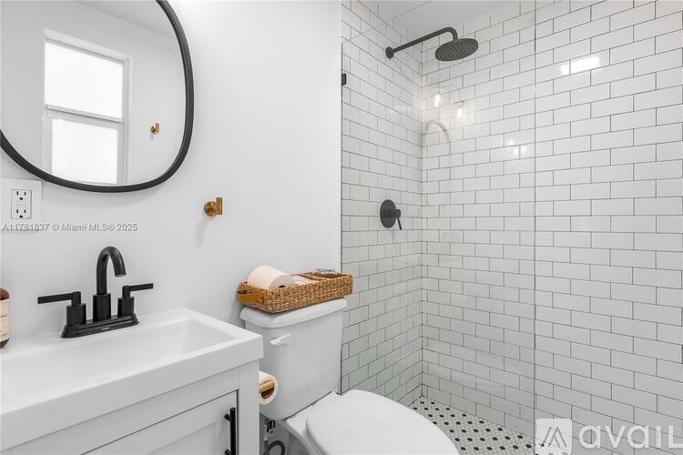 A white bathroom with a round mirror and a white toilet.