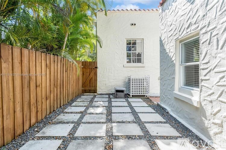 A white house with a wooden fence and a stone pathway leading to the door.
