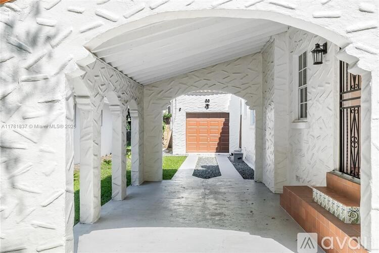 A white arched passageway leads to a door.