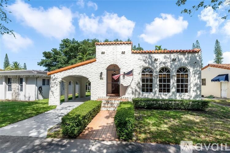 A white house with a red tile roof and a flag on the front door.