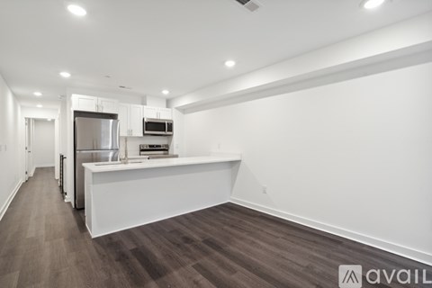 A spacious kitchen with white cabinets and a wooden floor.