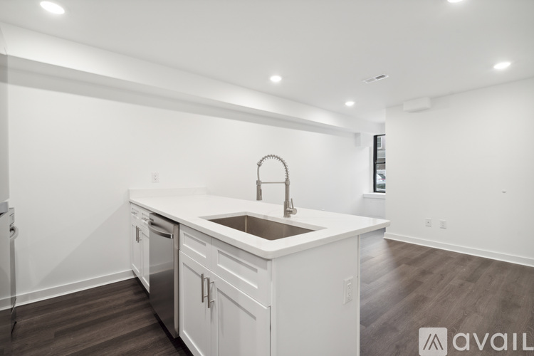 A modern kitchen with white cabinets and a wooden floor.