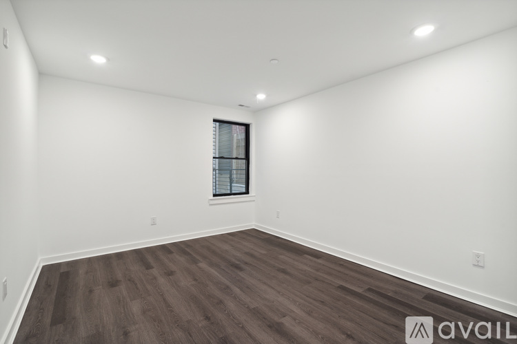 A spacious room with wooden flooring and a window.