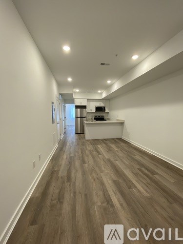 A long hallway with wood floors and white walls.