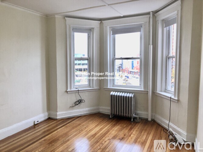 A room with wood floors and three windows.