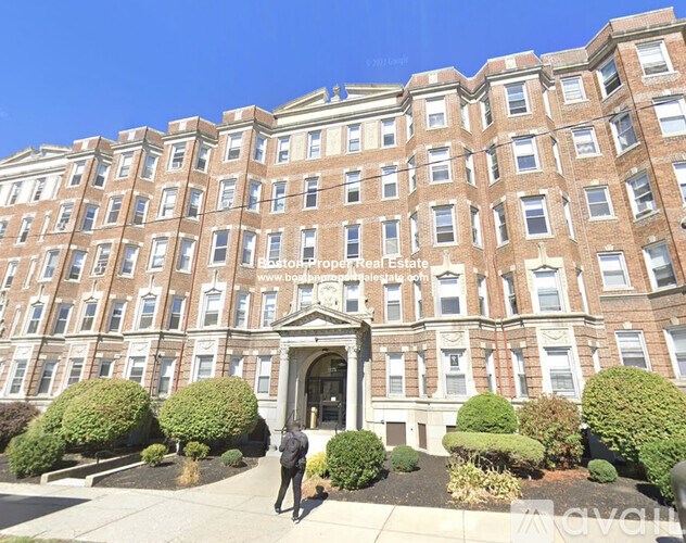 A large red brick building with a man walking in front of it.