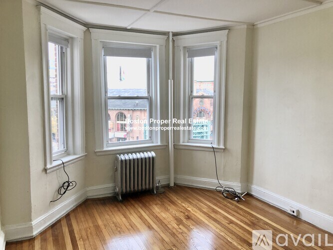 A room with wooden floors and a window overlooking a cityscape.