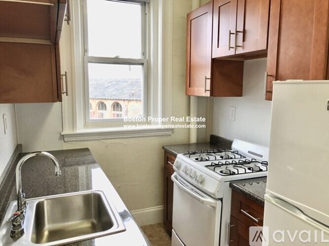 A kitchen with a stove, sink, and cabinets.