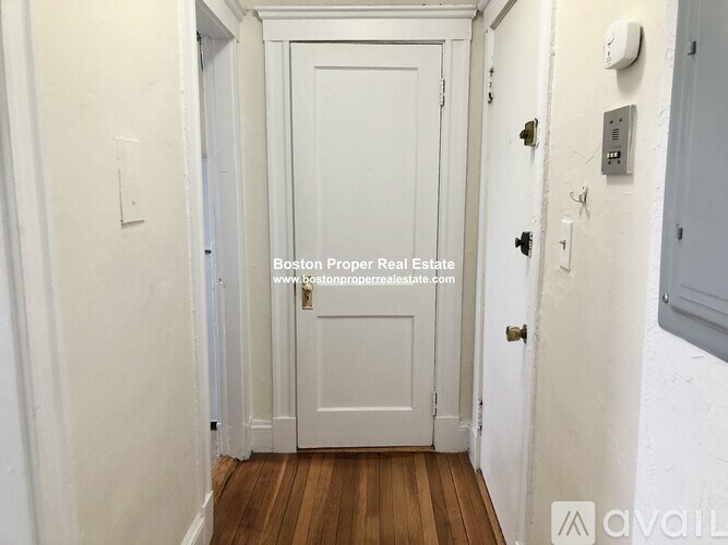 A white door with a brass handle is in the middle of a hallway.