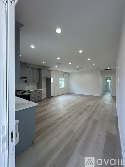 A kitchen with a refrigerator and wooden floors.