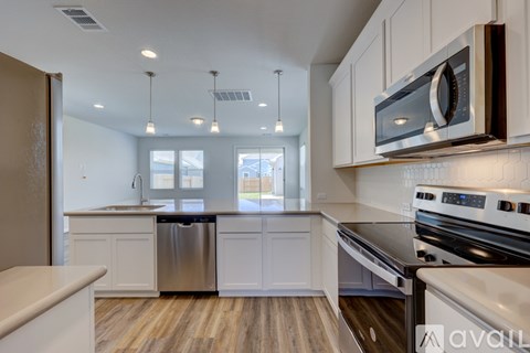 A modern kitchen with white cabinets and stainless steel appliances.