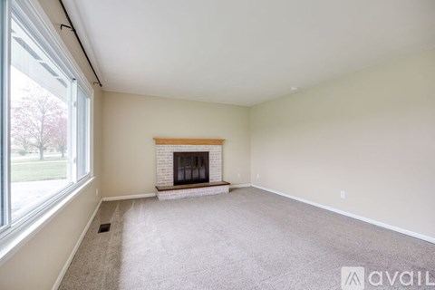 A spacious living room with a fireplace and large windows.