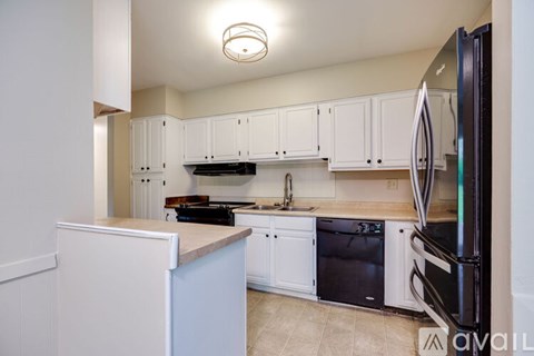 A kitchen with white cabinets and a black refrigerator.