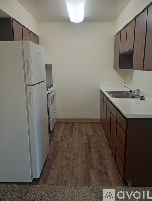 A kitchen with a white fridge and wooden cabinets.