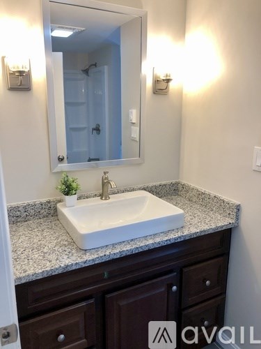 A bathroom with a white sink and brown drawers.