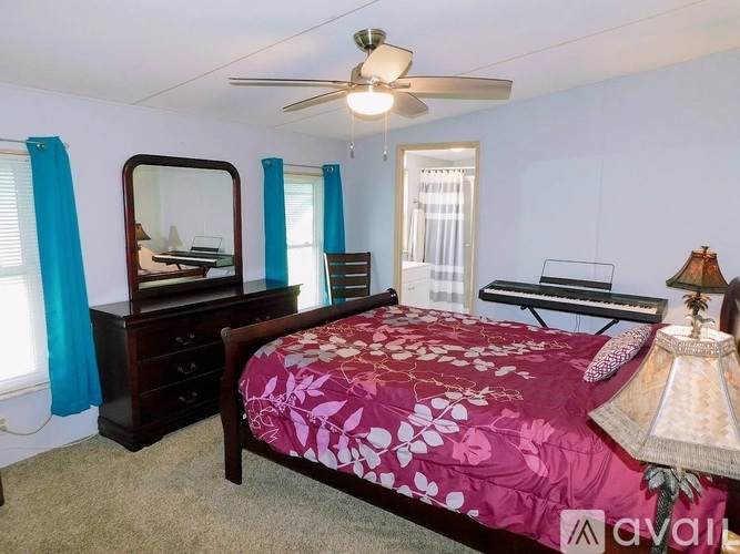 Bedroom with a bed, dresser, mirror, and a fan.