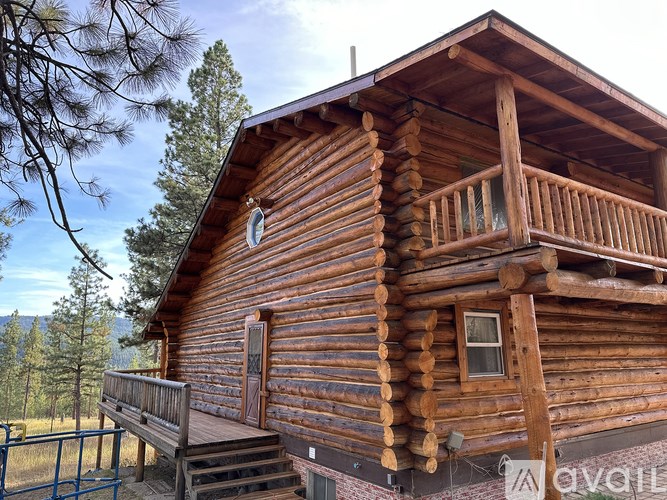 A wooden cabin with a balcony and a deck.