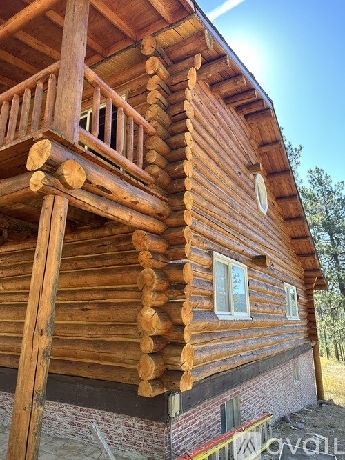 A wooden cabin with a balcony and windows.