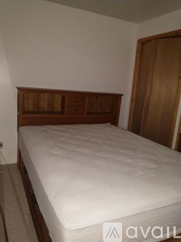 A bed with a wooden headboard and white sheets sits in a room.