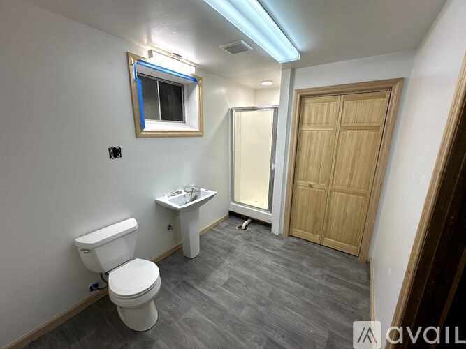 A bathroom with a toilet, sink, and window.