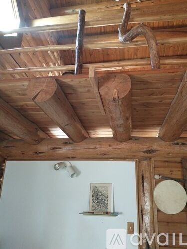 A wooden beam is supported by a white wall.