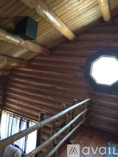 A wooden cabin with a window and a speaker on the ceiling.