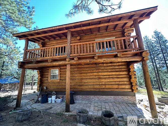 A wooden cabin with a balcony is surrounded by trees.