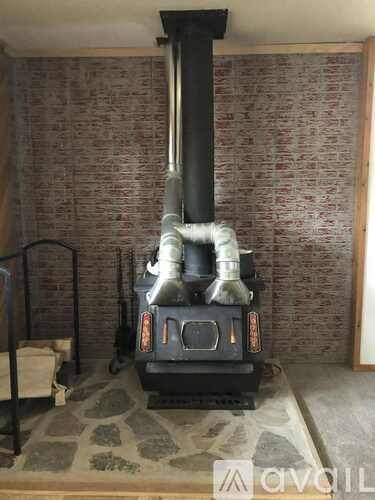 A wood stove in a room with a brick wall.