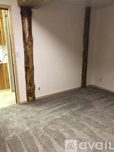 A room with a carpeted floor and a wooden pillar.