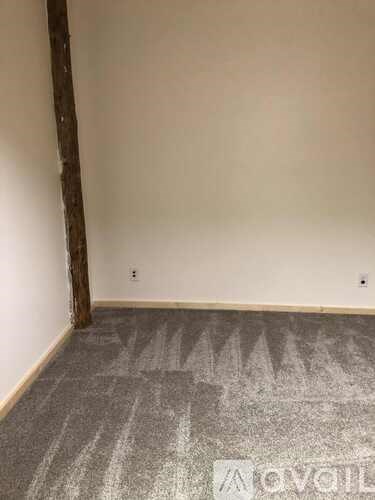 A room with a grey carpet and a white wall.