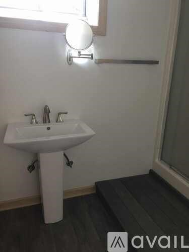 A white pedestal sink with a chrome faucet and a wall-mounted light fixture.